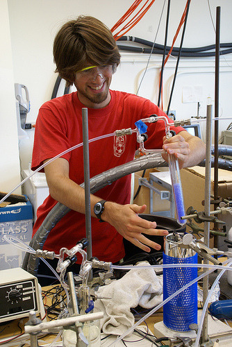 Student in a lab, surrounded by tubes and wires.